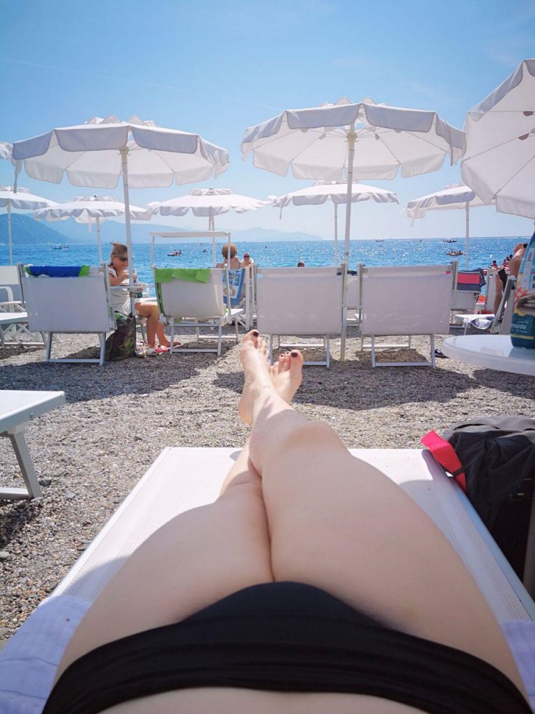 International travel companion Sir Claire Black in a bikini lying on the beach in Italy